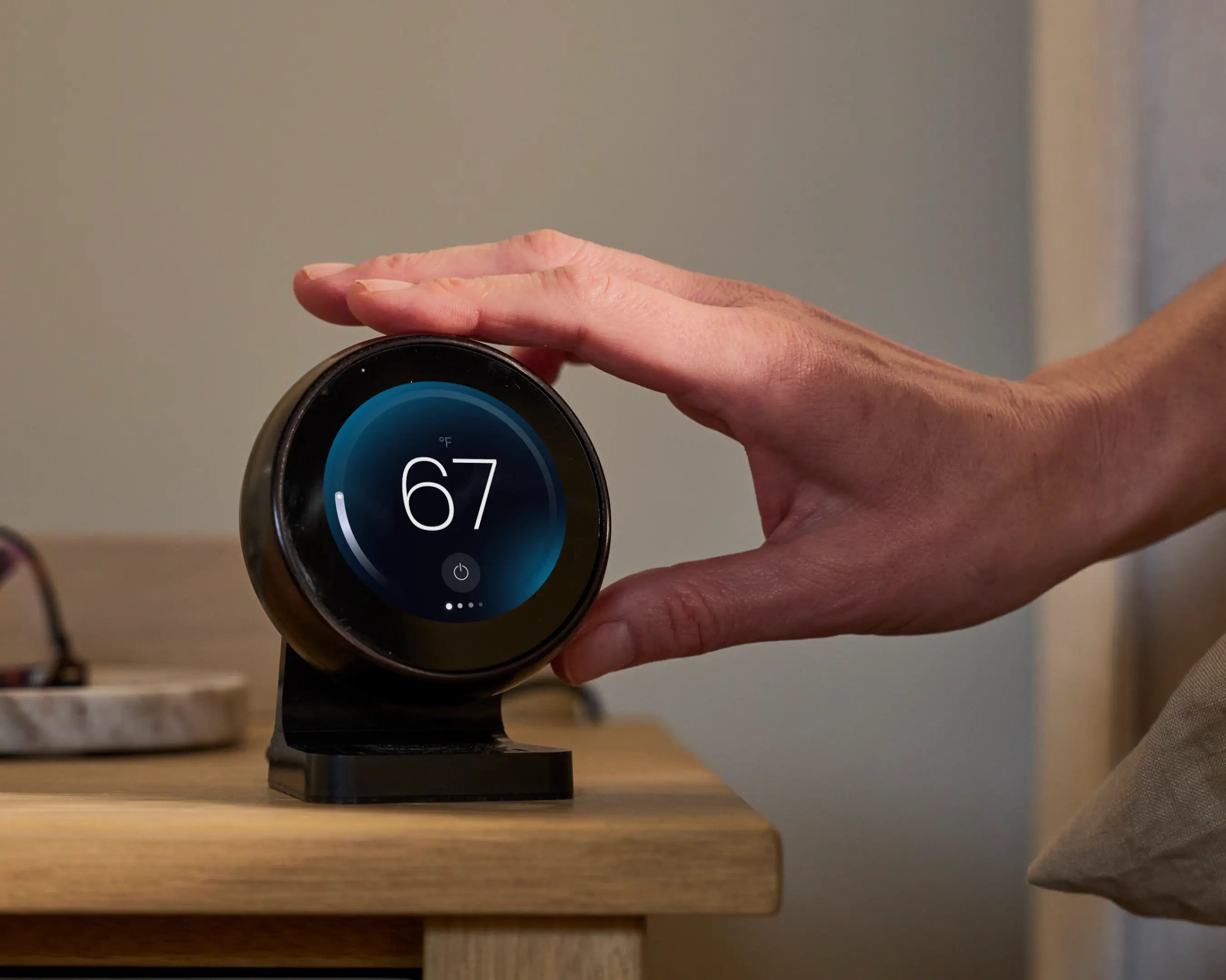 Smart home device with digital display held by a hand on a wooden surface