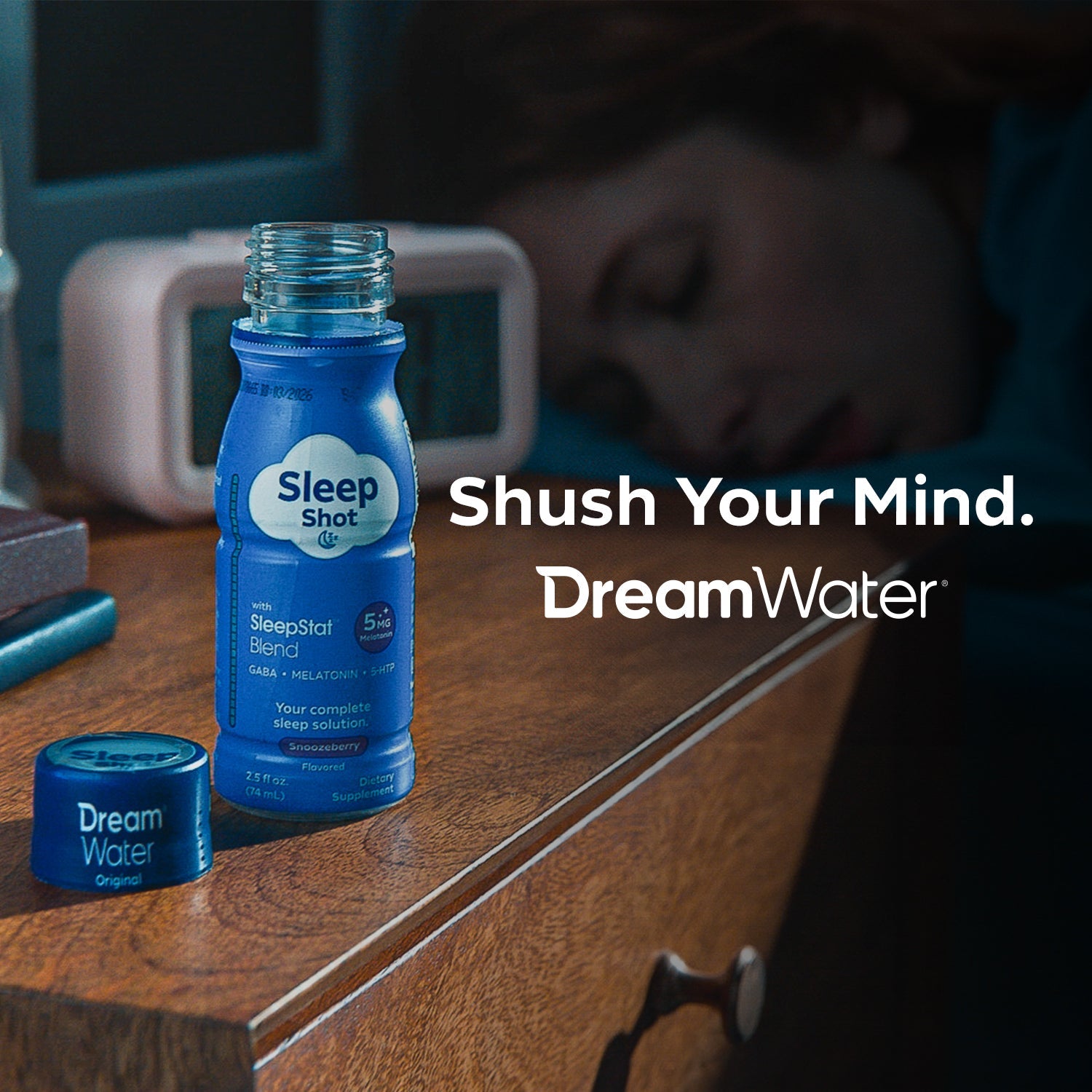 Sleep Shot bottle with DreamWater packaging on a nightstand, with a person sleeping in the background.