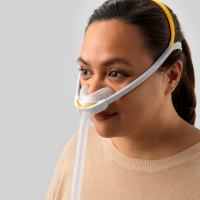 Female side sleeper smiling while wearing Fisher & Paykel Solo AutoFit nasal CPAP mask