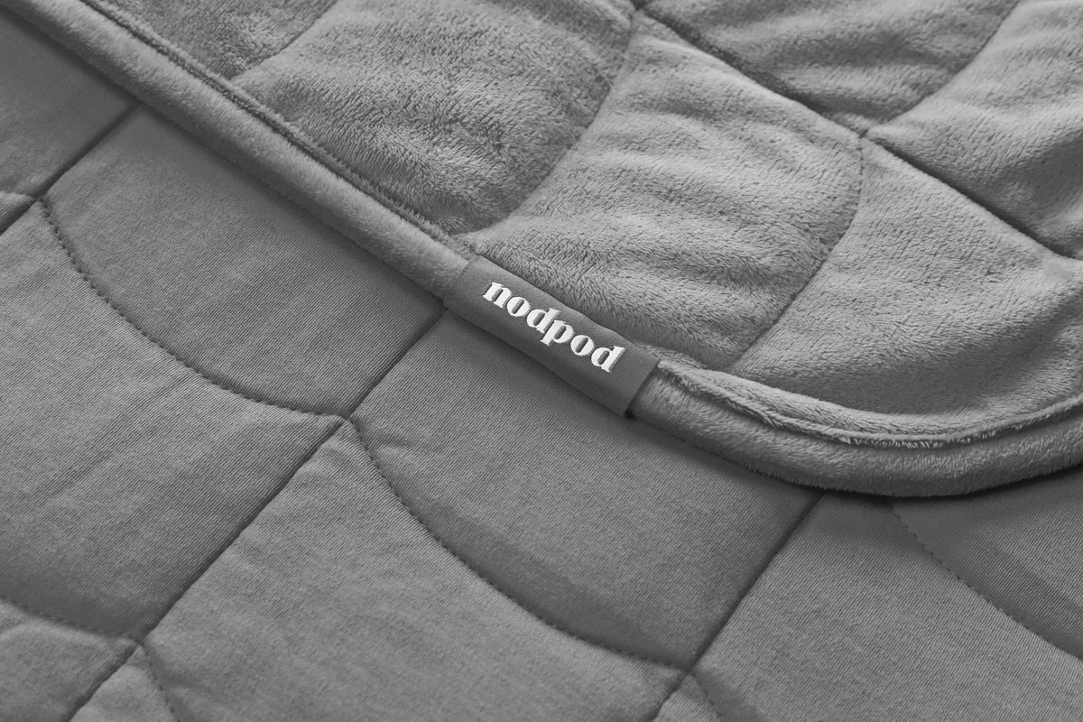 Folded Nodpod BODY weighted blanket in elephant gray displaying compact storage roll
