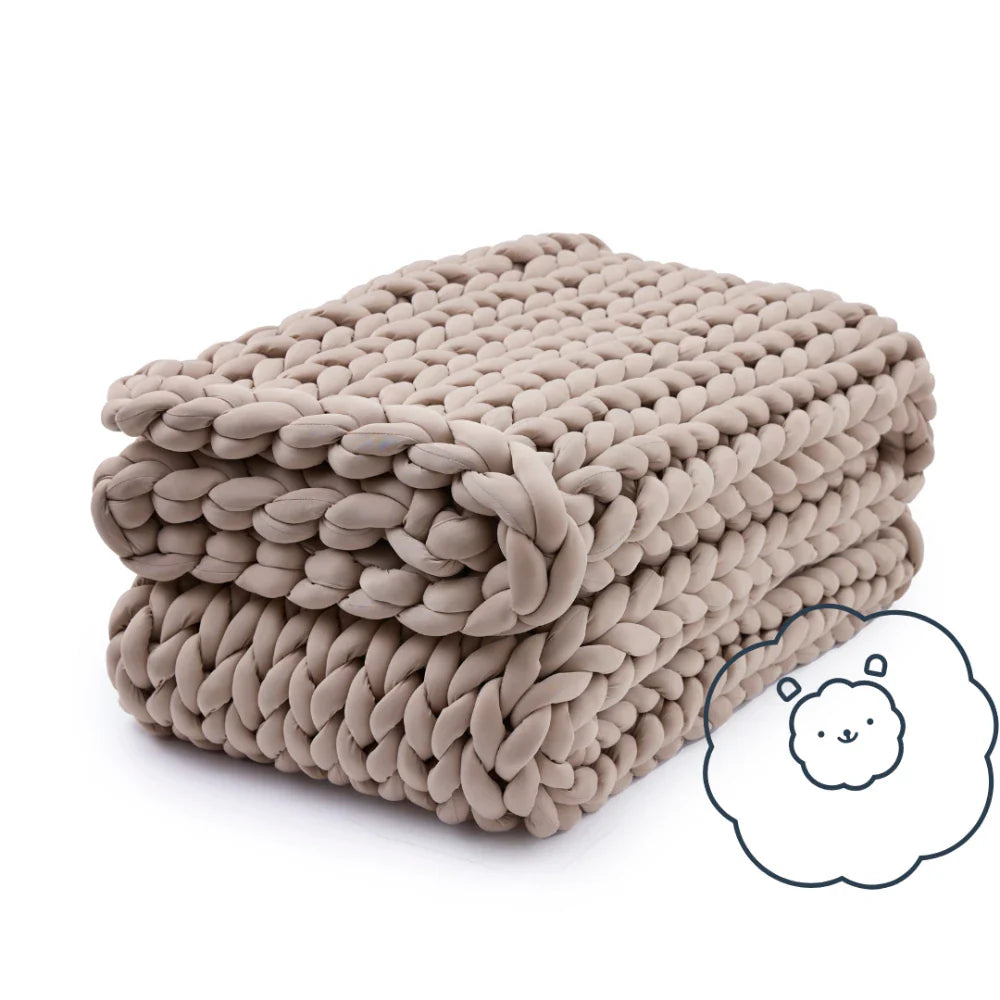 Folded Nuzzie Ice Knit cooling weighted blanket in coastal sand on bedroom bench