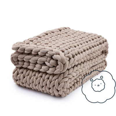 Folded Nuzzie Ice Knit cooling weighted blanket in coastal sand on bedroom bench