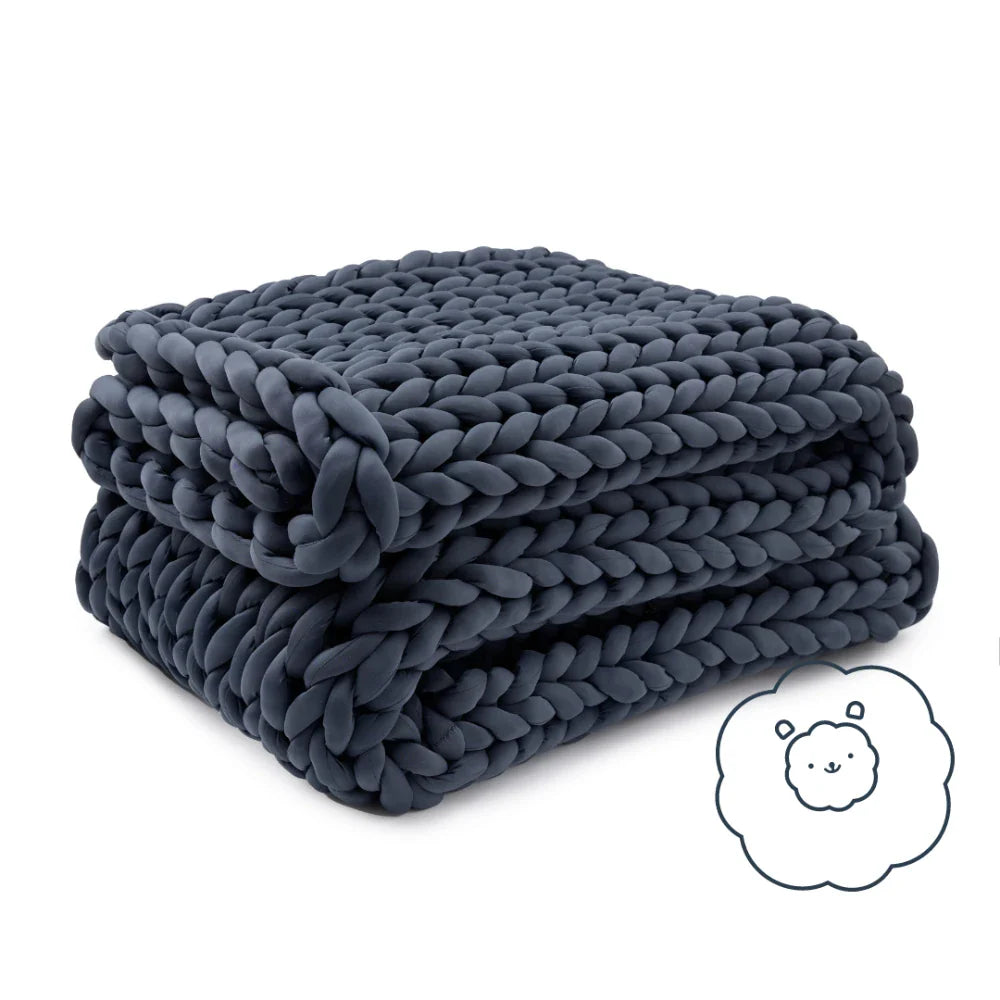 Folded Nuzzie Ice Knit cooling weighted blanket in northern grey resting on modern bed