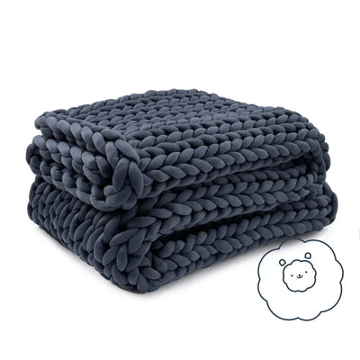 Folded Nuzzie Ice Knit cooling weighted blanket in northern grey resting on modern bed