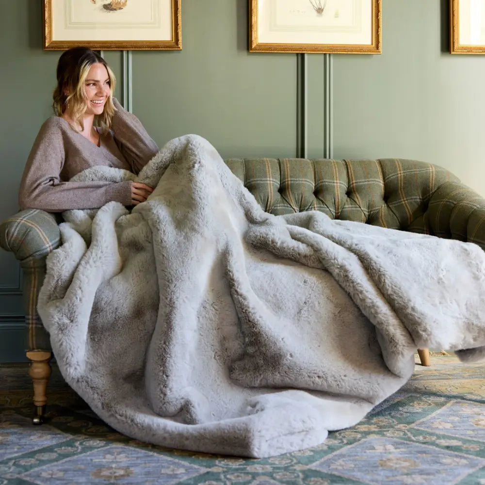 Folded Nuzzie Snuggle Luxe chunky blanket in earl grey placed on wooden bench