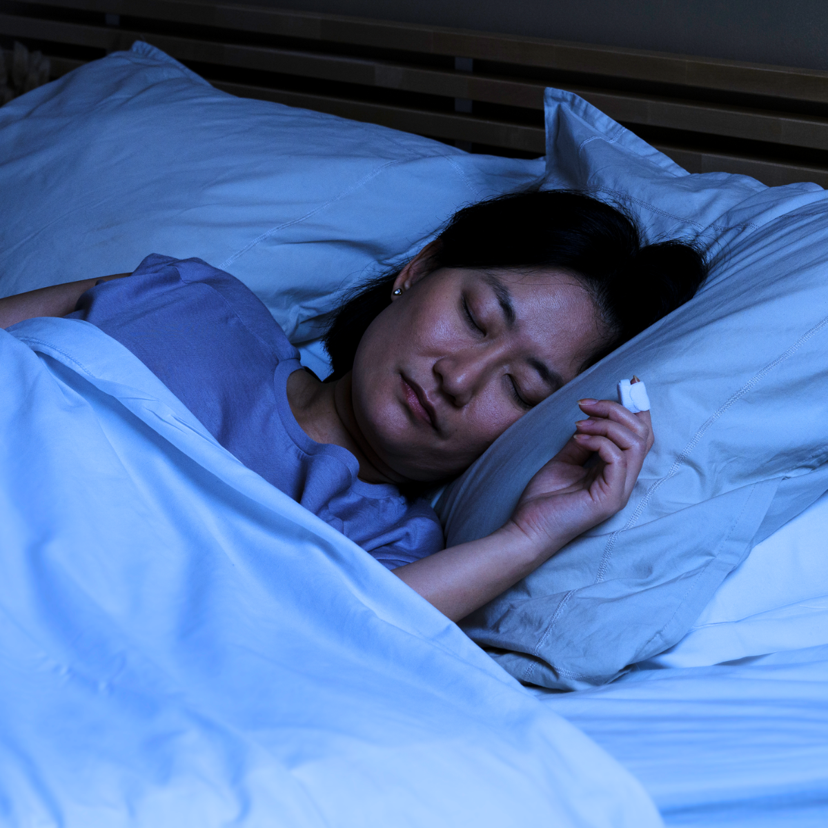 Woman sleeping at home while wearing lightweight NightOwl sensor for sleep apnea analysis