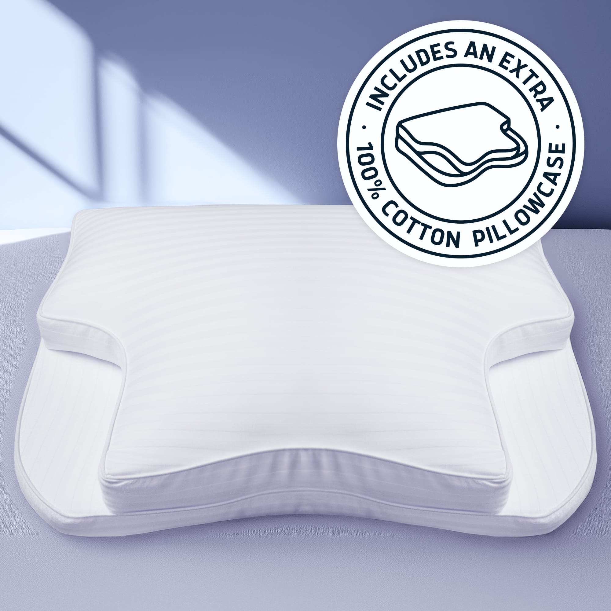 A white contoured pillow with a matching white pillowcase, shown on a soft lavender background with a circular badge in the top right that reads 'INCLUDES AN EXTRA 100% COTTON PILLOWCASE'.