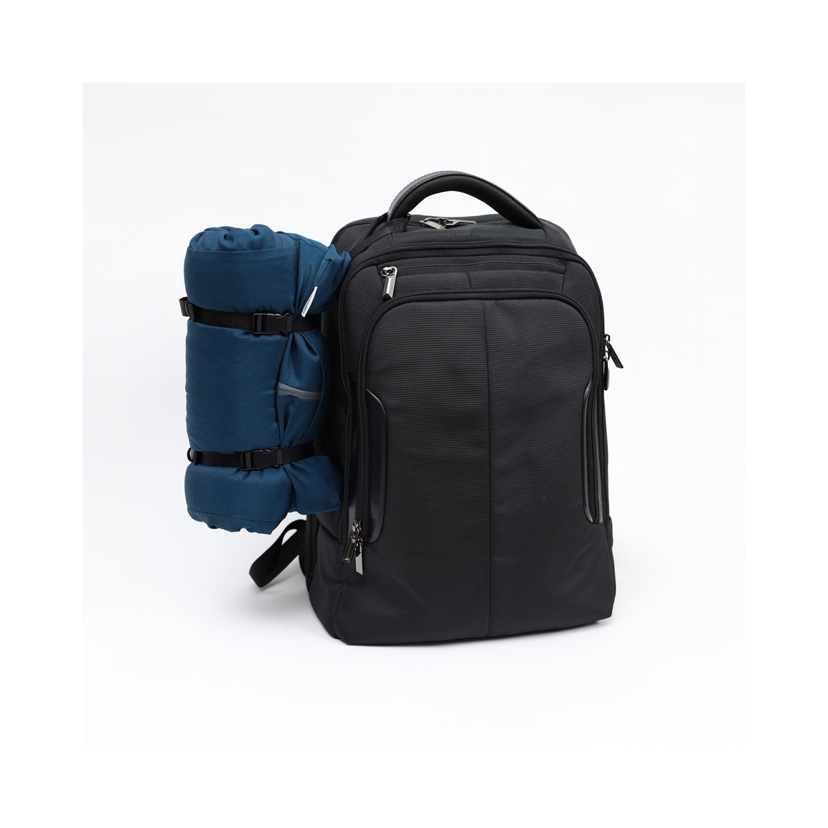 A black backpack shown on a white studio background, with a rolled blue sleeping bag or camping pad strapped to its side.