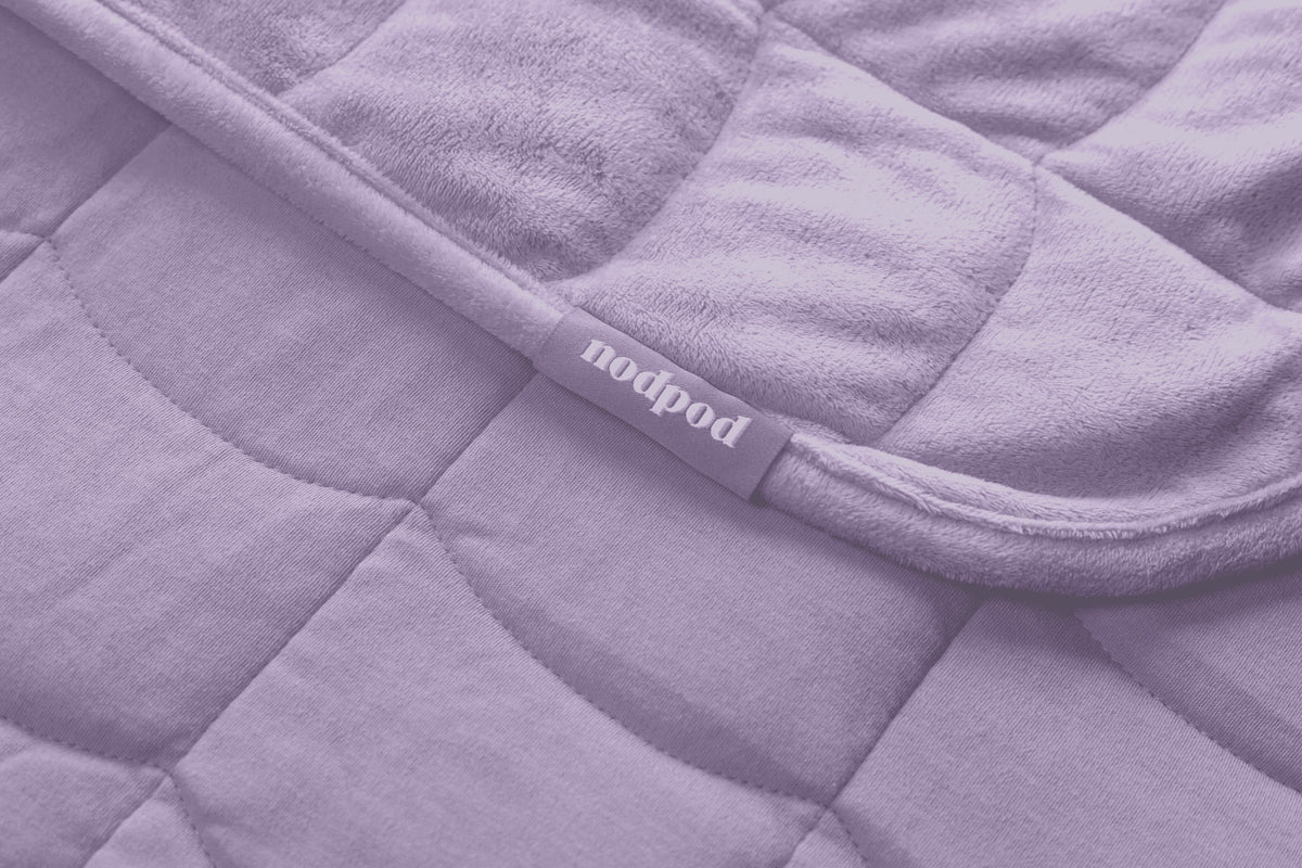 Nodpod BODY weighted pod blanket in soothing wisteria purple displayed on neutral backdrop