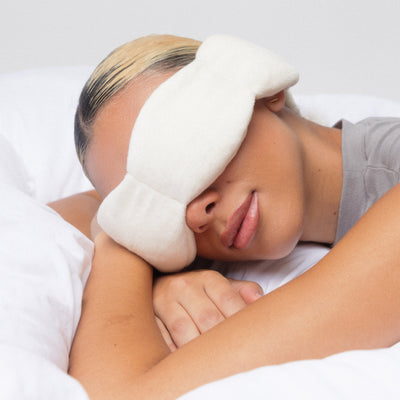 Model sleeping soundly on back wearing Nodpod bone weighted eye mask