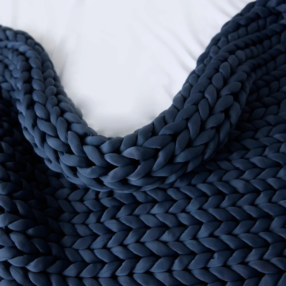 Nuzzie Ice Knit cooling weighted blanket in rich pacific blue draped across living room sofa