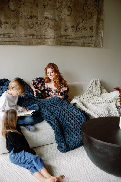 Nuzzie knit weighted blanket in Dusty Blue, with kids on a couch