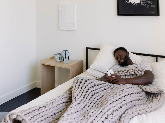 Nuzzie knit weighted blanket in Dusty Rose, draped over a person relaxing