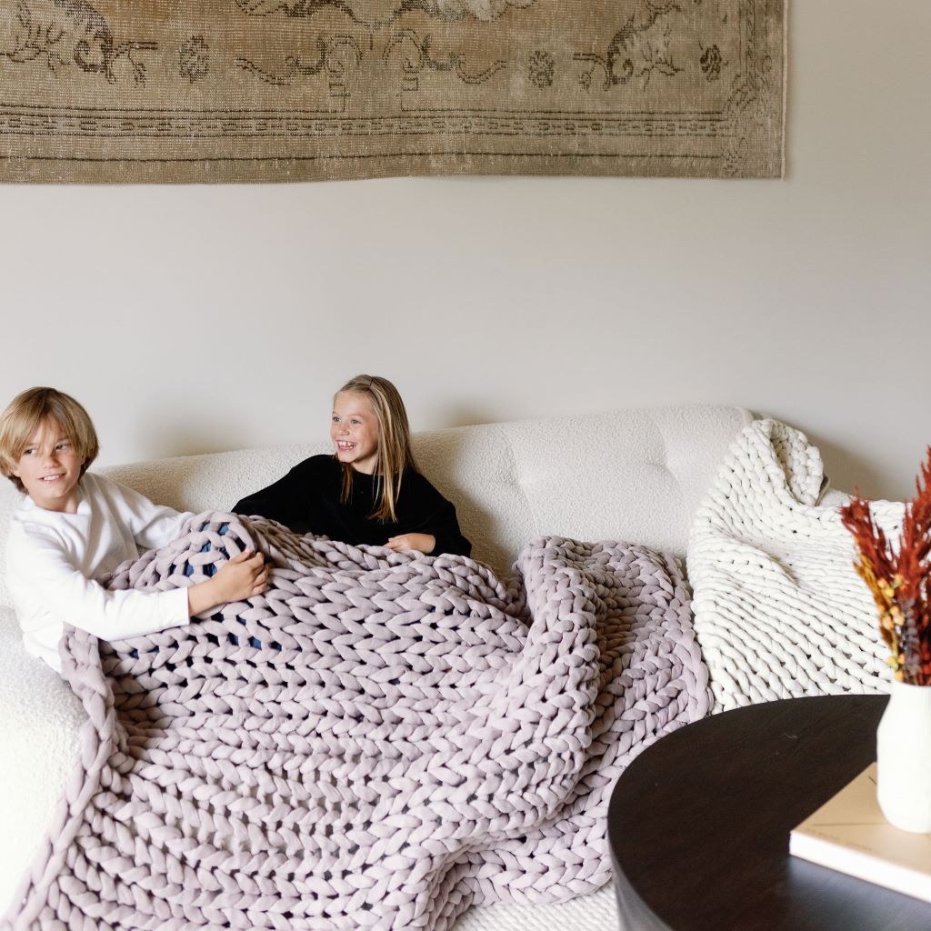 Nuzzie knit weighted blanket in Dusty Rose, used on a couch