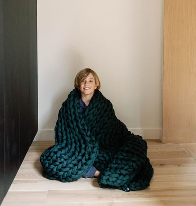 Nuzzie knit weighted blanket in Forest Green, with kids snuggled underneath
