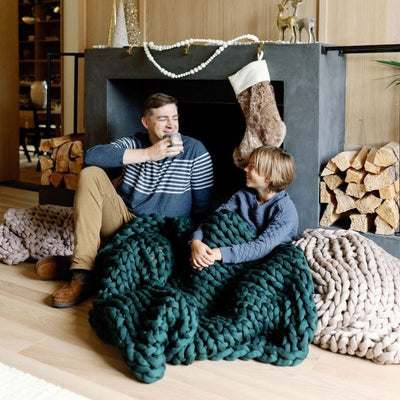 Nuzzie knit weighted blanket in Forest Green, draped over a person relaxing