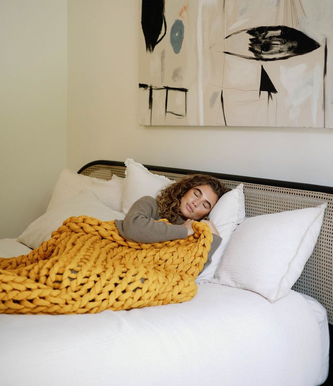 Nuzzie knit weighted blanket in Marigold, wrapped around a person