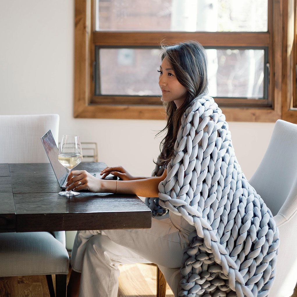 Nuzzie knit weighted blanket in Misty Grey, wrapped around a person