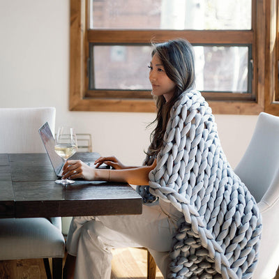 Nuzzie knit weighted blanket in Misty Grey, wrapped around a person