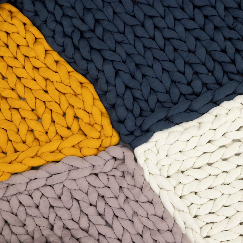 Nuzzie knit weighted blanket, draped over a person relaxing