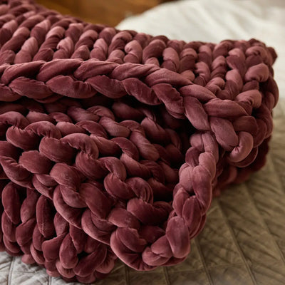 Nuzzie ruby red velvet weighted blanket arranged on neutral bedding background