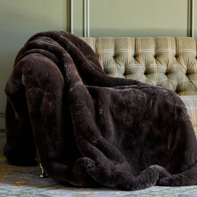 Nuzzie Snuggle Luxe chunky knit blanket in rich mocha brown draped over leather chair