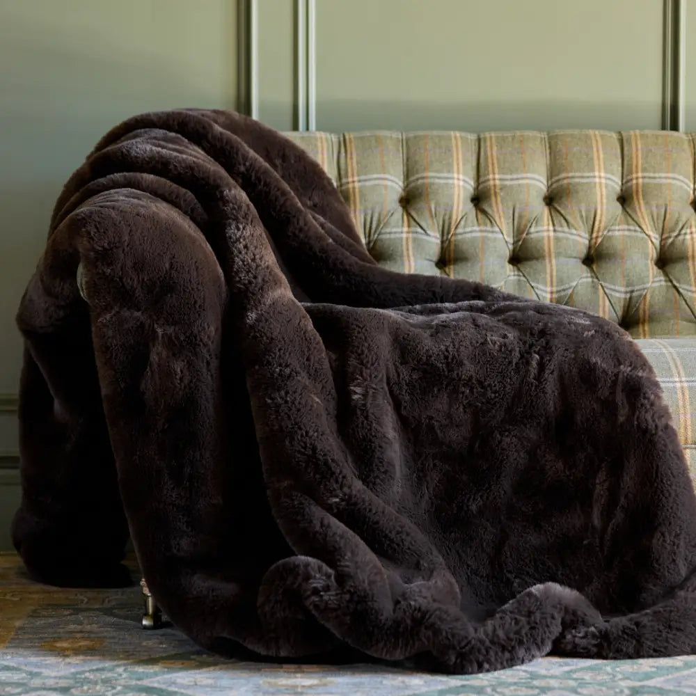 Nuzzie Snuggle Luxe chunky knit blanket in rich mocha brown draped over leather chair