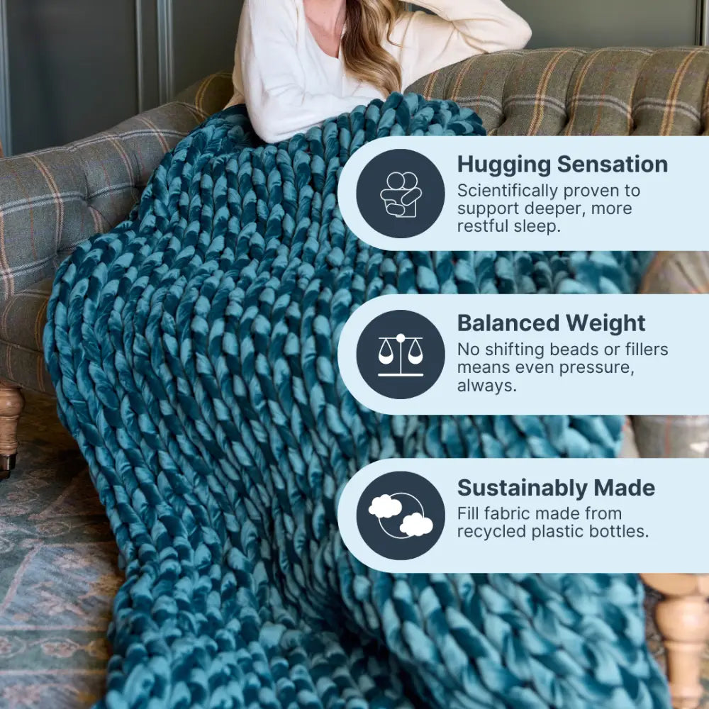Nuzzie sapphire blue velvet weighted blanket draped gracefully across sofa