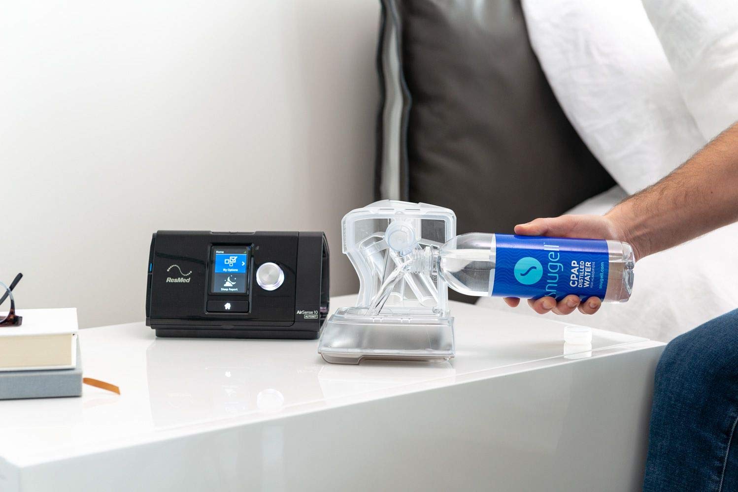 Person holding a water bottle next to a CPAP machine on a table.
