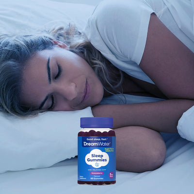 Woman lying in bed with a bottle of DreamWater Sleep Gummies on the bed.