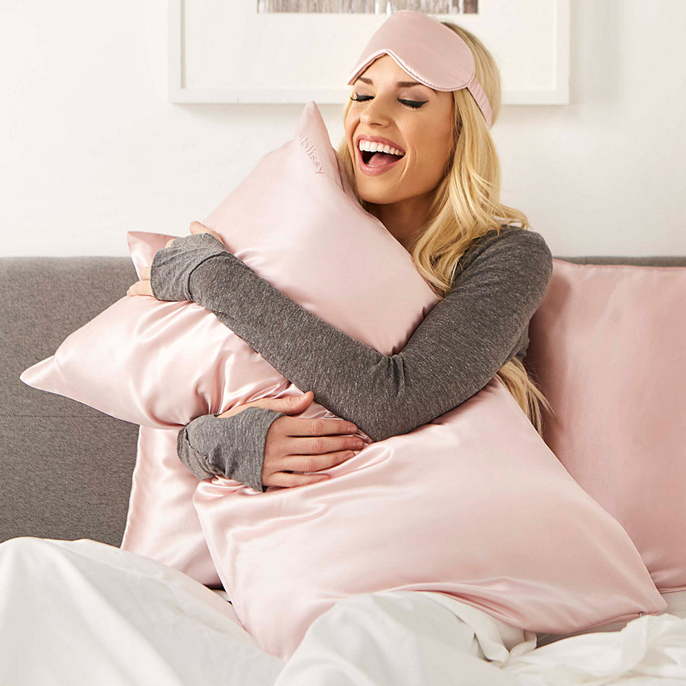 Woman resting comfortably while wearing Blissy pure mulberry silk sleep mask in pink